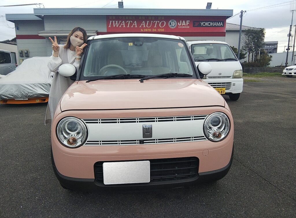 画像：ピンクの車の横に立つ女性