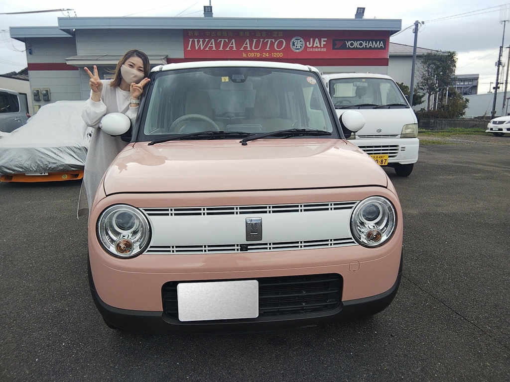 画像：ピンクの車の横に立つ女性