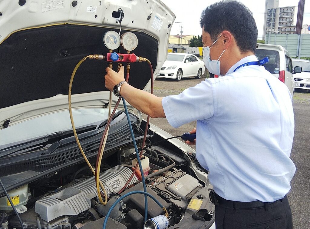 画像：車のバンパーを開けて作業をする男性